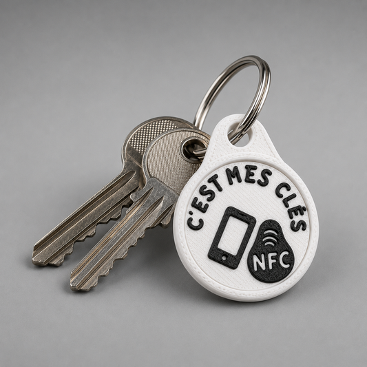 Two metal keys on a ring with a round white plastic NFC tag printed with C’EST MES CLÉS and a phone icon.